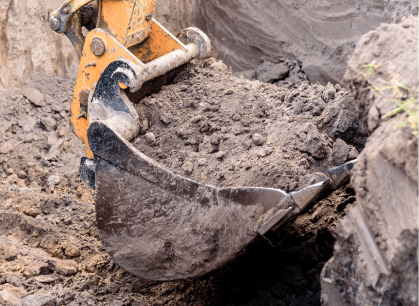 A construction worker using a shovel to dig a hole at a construction site